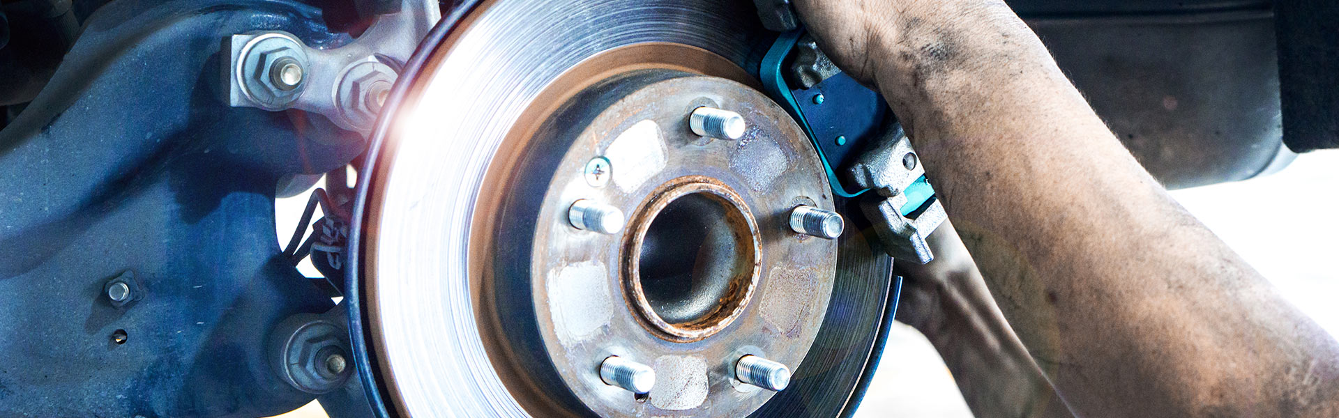 A mechanic installing new brake pads on a vehicle's disc brake rotor assembly.